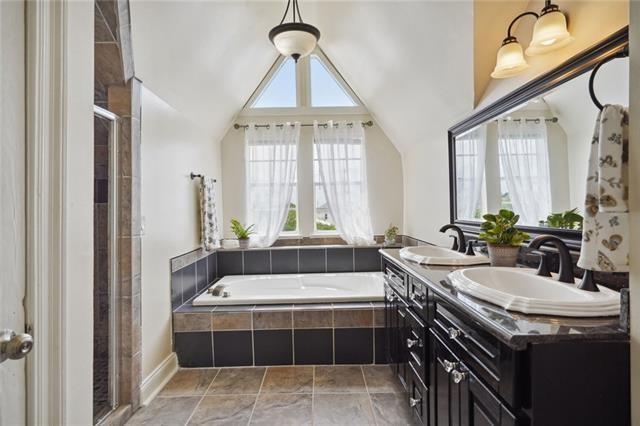 bathroom featuring vanity, vaulted ceiling, and separate shower and tub