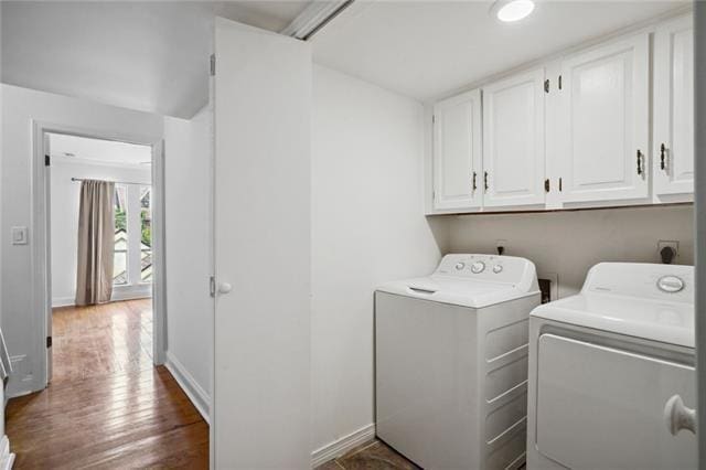 laundry area featuring cabinets, dark hardwood / wood-style flooring, and washing machine and clothes dryer