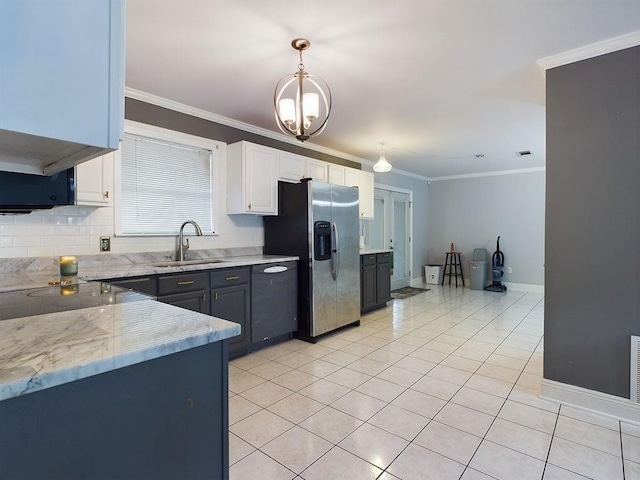 kitchen with white cabinets, stainless steel fridge, decorative light fixtures, and sink