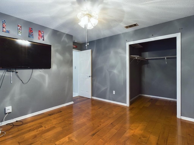 unfurnished bedroom with hardwood / wood-style floors, a textured ceiling, and a closet