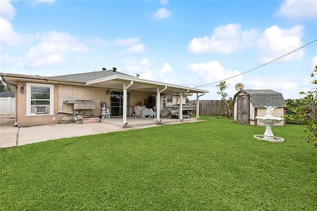 rear view of property with a lawn, a patio, and a storage shed