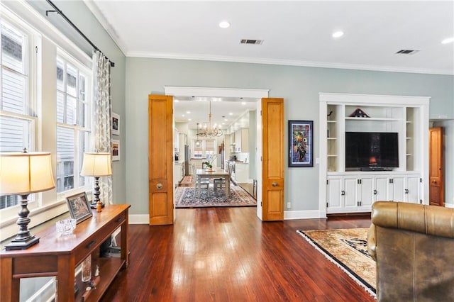 living room featuring dark hardwood / wood-style flooring, a chandelier, and ornamental molding