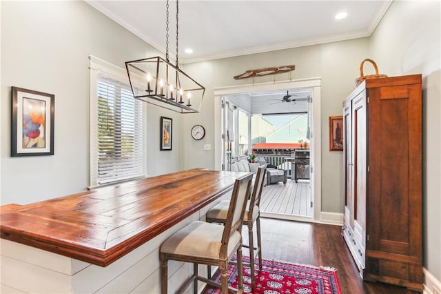 dining space featuring a wealth of natural light, dark wood-type flooring, ceiling fan with notable chandelier, and ornamental molding