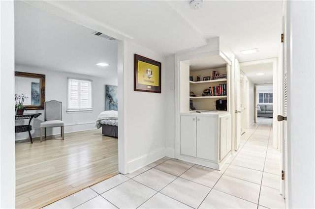 hallway featuring built in shelves and light hardwood / wood-style floors