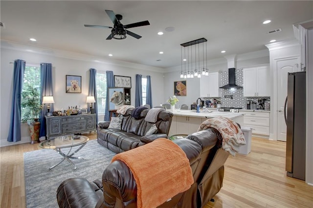 living room with ceiling fan, light wood-type flooring, ornamental molding, and a wealth of natural light