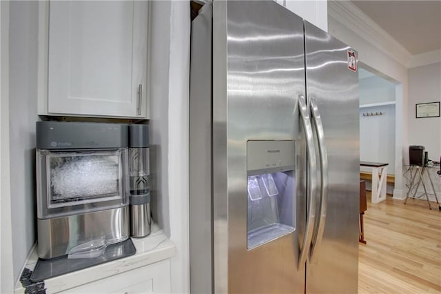 kitchen featuring white cabinetry, stainless steel fridge, light hardwood / wood-style flooring, and ornamental molding