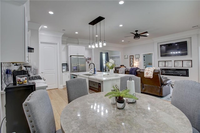 dining space with ceiling fan, light hardwood / wood-style floors, sink, and crown molding