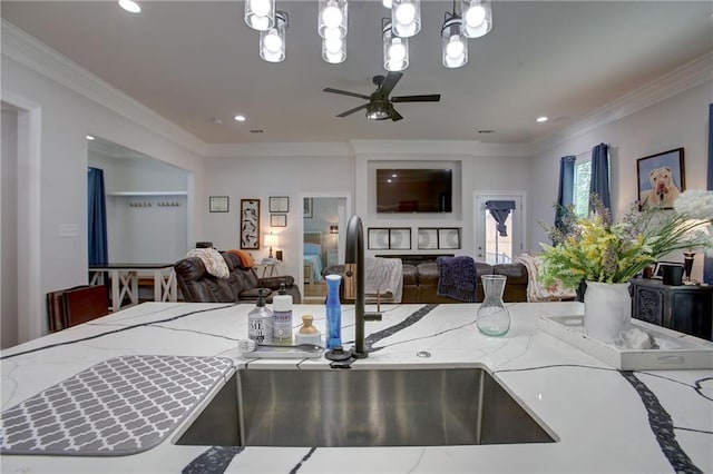 kitchen featuring pendant lighting, ceiling fan with notable chandelier, light stone counters, and crown molding