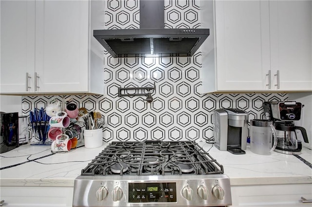 kitchen with white cabinets, light stone countertops, and wall chimney range hood