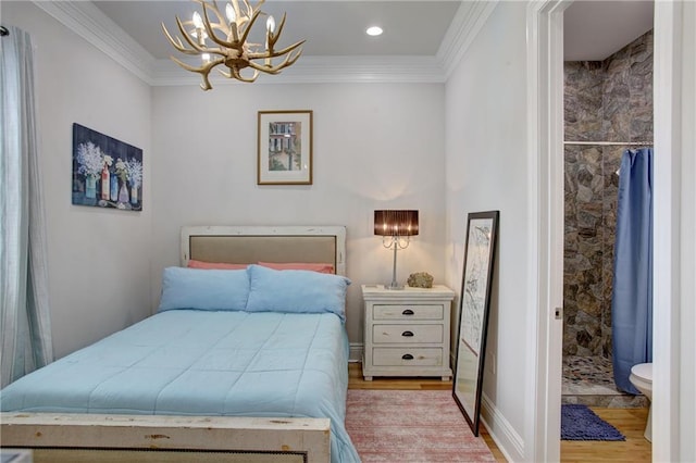 bedroom featuring light hardwood / wood-style floors, ensuite bath, ornamental molding, and a notable chandelier