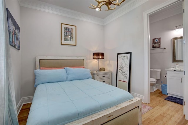 bedroom featuring an inviting chandelier, light wood-type flooring, crown molding, and ensuite bath