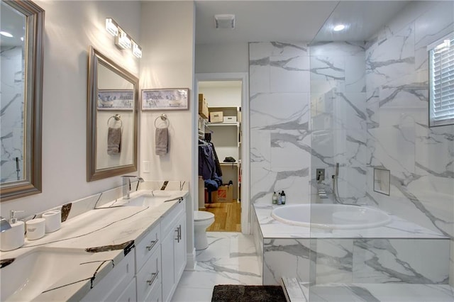 bathroom with tiled bath, vanity, and toilet