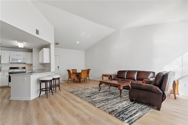 living room with light hardwood / wood-style floors, lofted ceiling, and sink