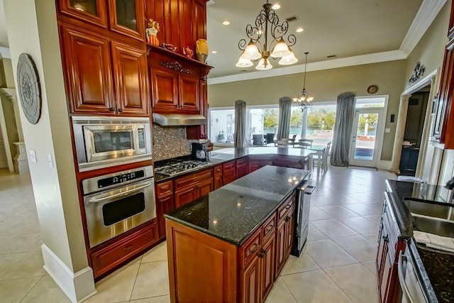 kitchen with decorative light fixtures, dark stone countertops, appliances with stainless steel finishes, a notable chandelier, and a kitchen island