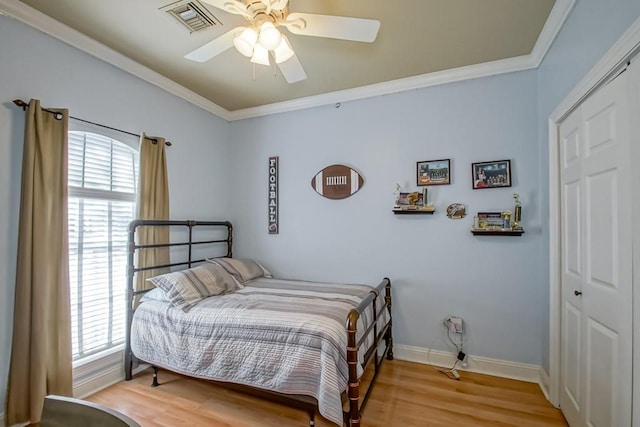 bedroom with a closet, multiple windows, hardwood / wood-style flooring, and ceiling fan