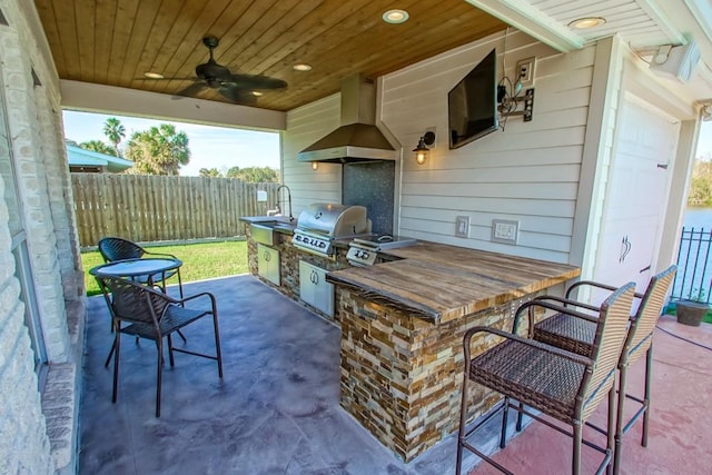 view of patio / terrace with ceiling fan, an outdoor kitchen, a grill, and an outdoor wet bar