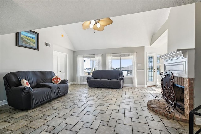 living room featuring ceiling fan, a fireplace, high vaulted ceiling, and a textured ceiling