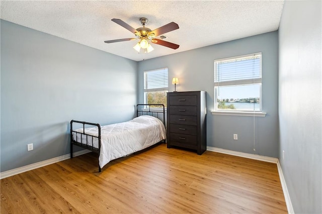 bedroom with a textured ceiling, light hardwood / wood-style floors, and ceiling fan