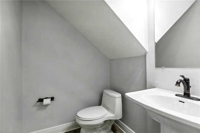 bathroom with vaulted ceiling, toilet, and sink