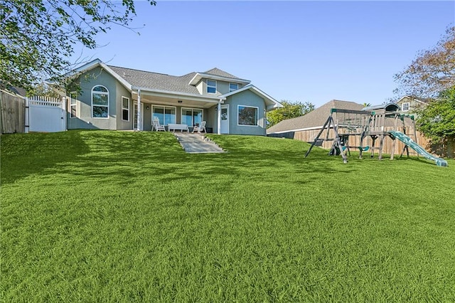 rear view of house with a playground, a patio area, and a lawn