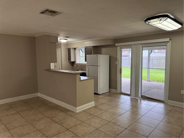 kitchen with kitchen peninsula, white fridge, a healthy amount of sunlight, and light tile patterned floors