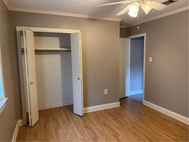 unfurnished bedroom with ceiling fan, crown molding, a textured ceiling, a closet, and light wood-type flooring