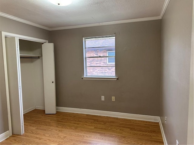 unfurnished bedroom featuring crown molding, a closet, light hardwood / wood-style floors, and a textured ceiling