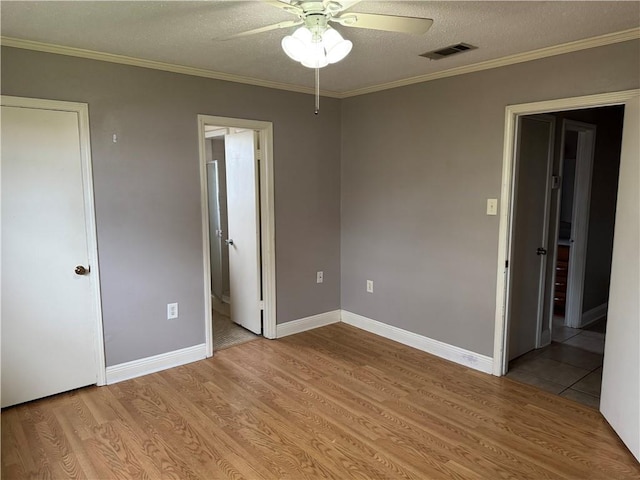 unfurnished bedroom with light wood-type flooring, ensuite bathroom, ornamental molding, a textured ceiling, and ceiling fan