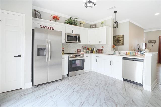 kitchen with white cabinets, crown molding, stainless steel appliances, and hanging light fixtures