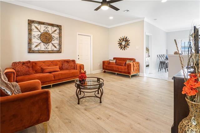 living room with wood-type flooring, ceiling fan, and ornamental molding