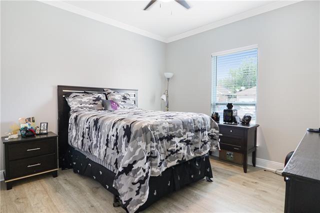 bedroom with light wood-type flooring, ceiling fan, and ornamental molding