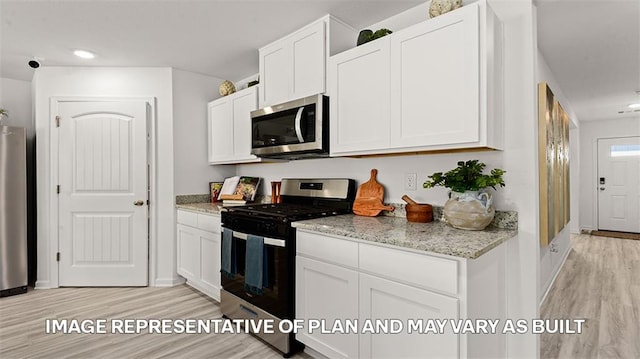 kitchen with appliances with stainless steel finishes, light hardwood / wood-style flooring, and white cabinetry