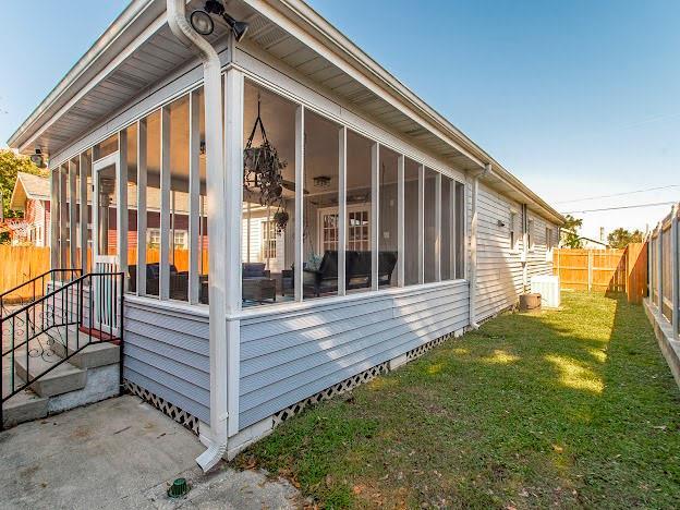 view of side of home with a lawn and a sunroom