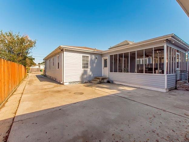 rear view of property featuring a sunroom and a patio area