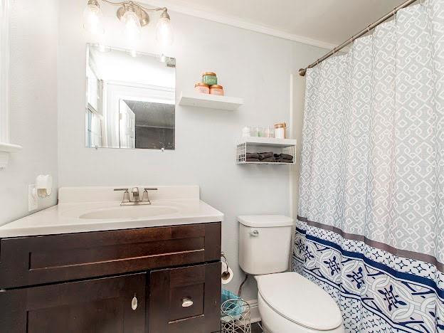 bathroom with crown molding, vanity, and toilet