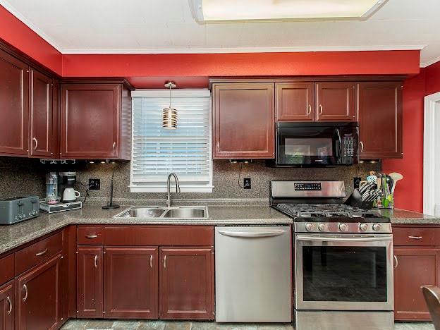 kitchen with pendant lighting, sink, crown molding, and appliances with stainless steel finishes