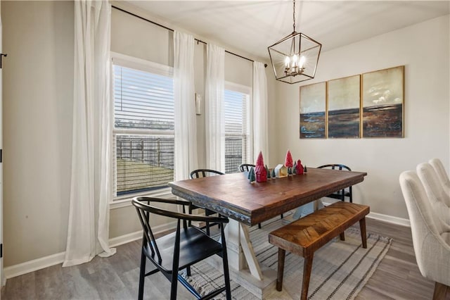 dining space with hardwood / wood-style floors and a notable chandelier