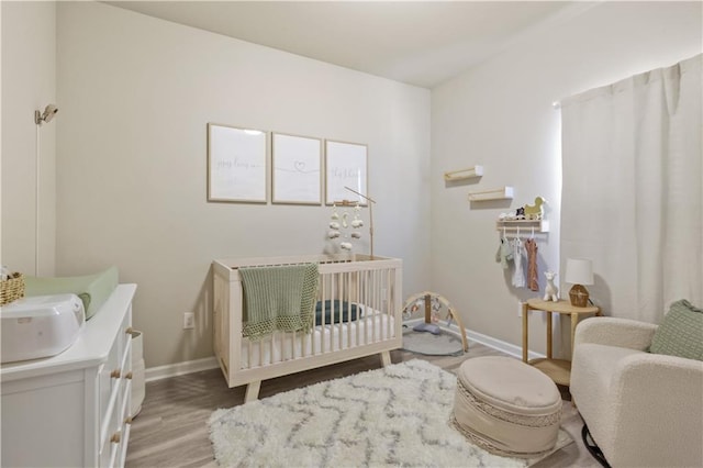 bedroom with a crib and light hardwood / wood-style flooring