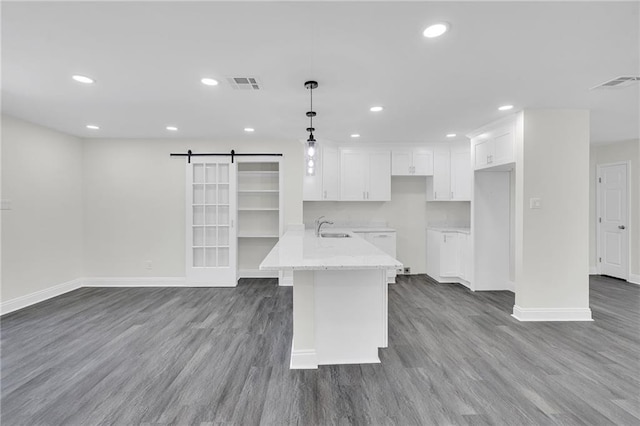 kitchen featuring a barn door, white cabinetry, hanging light fixtures, and wood-type flooring