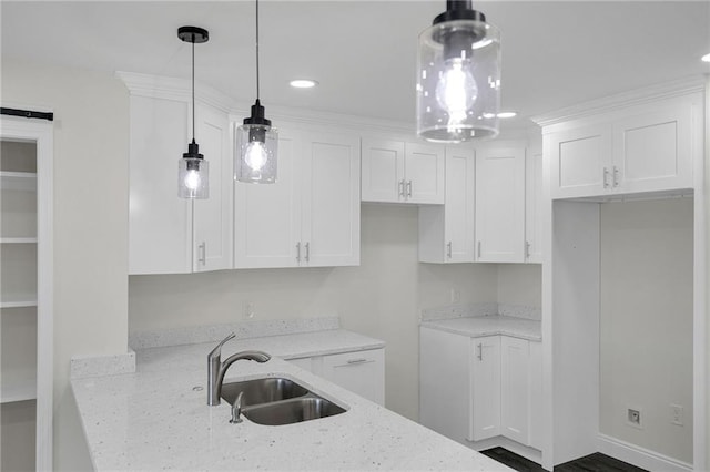 kitchen featuring light stone countertops, decorative light fixtures, white cabinetry, and sink