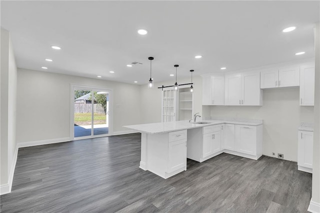 kitchen with hardwood / wood-style flooring, decorative light fixtures, white cabinetry, and kitchen peninsula