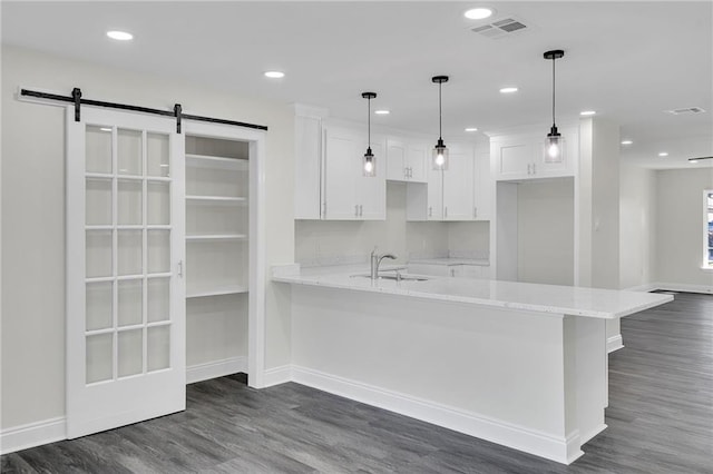 kitchen featuring white cabinetry, sink, light stone countertops, dark wood-type flooring, and a barn door