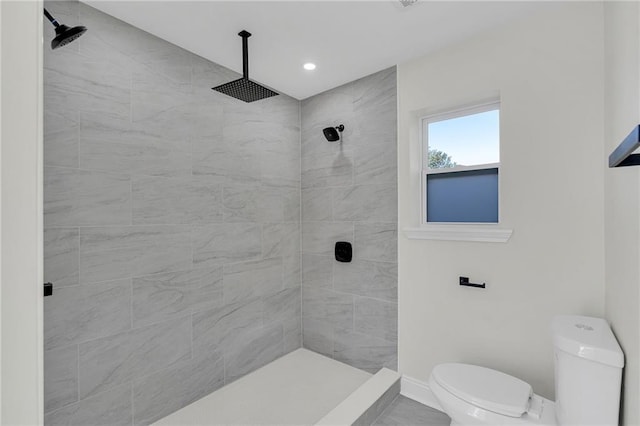 bathroom with a tile shower and toilet