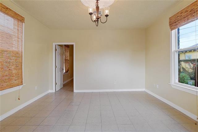 tiled spare room featuring a healthy amount of sunlight and an inviting chandelier