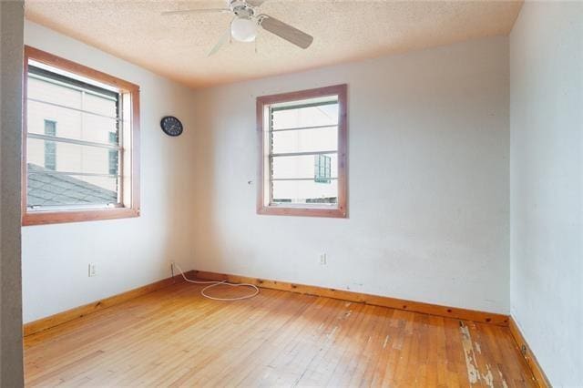 unfurnished room featuring ceiling fan, a textured ceiling, a wealth of natural light, and light hardwood / wood-style flooring