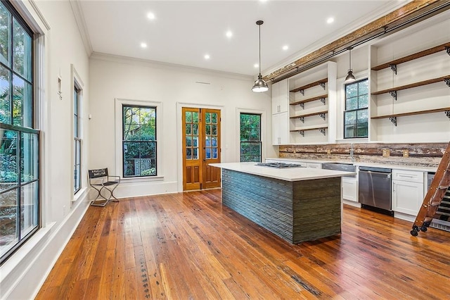 kitchen with ornamental molding, appliances with stainless steel finishes, a kitchen island, pendant lighting, and white cabinets