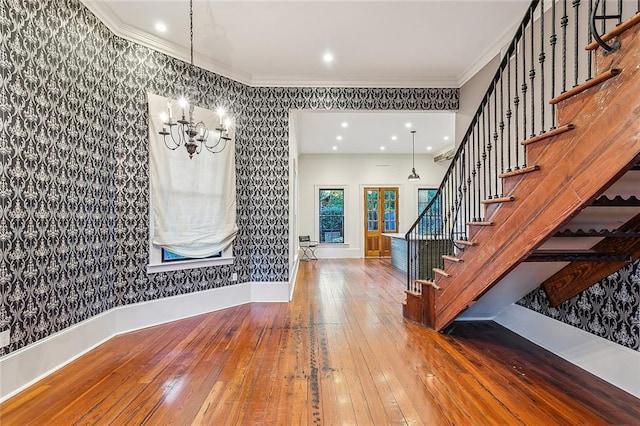 entrance foyer featuring hardwood / wood-style flooring, ornamental molding, and a notable chandelier