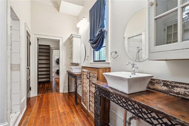 bathroom featuring stacked washer and dryer, wood-type flooring, sink, and a shower