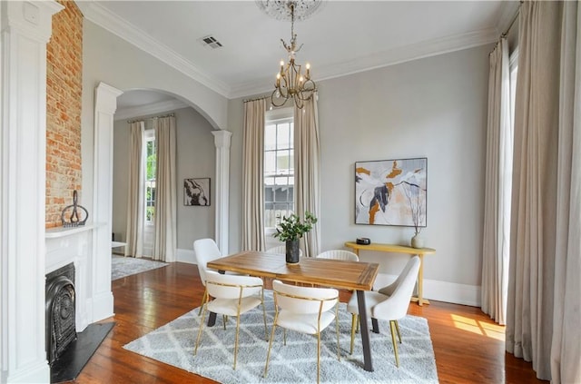 dining room featuring hardwood / wood-style floors, decorative columns, an inviting chandelier, and ornamental molding