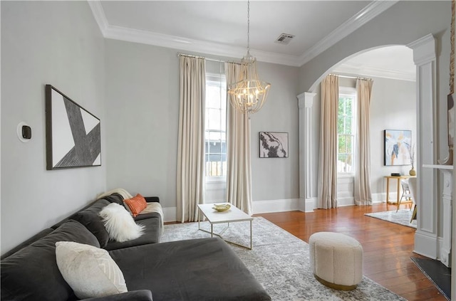 living room featuring hardwood / wood-style floors, decorative columns, crown molding, and a chandelier